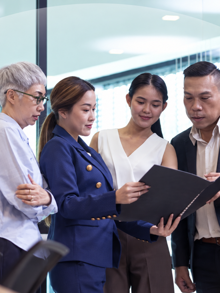 Four team members reviewing a document together in an office corridor